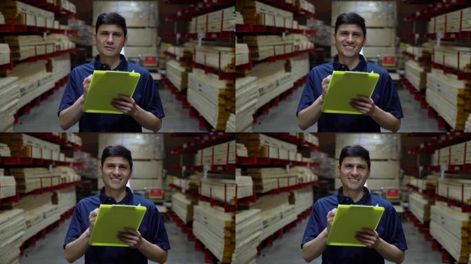 拉丁美洲男子使用剪贴板在配送仓库工作，然后面对相机微笑