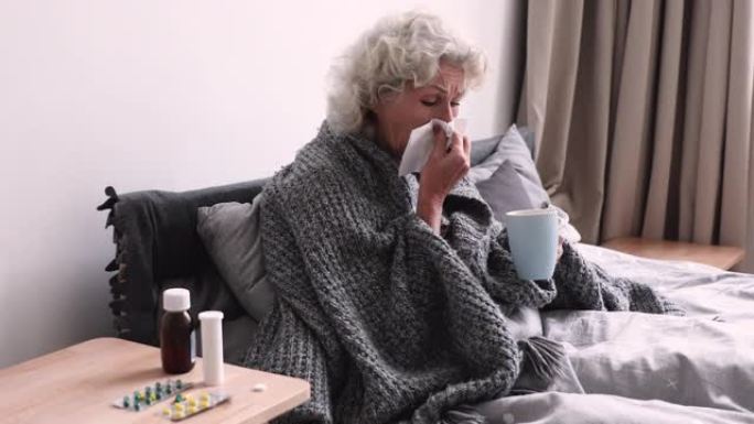 生病的老奶奶吹鼻子坐在床上感冒了