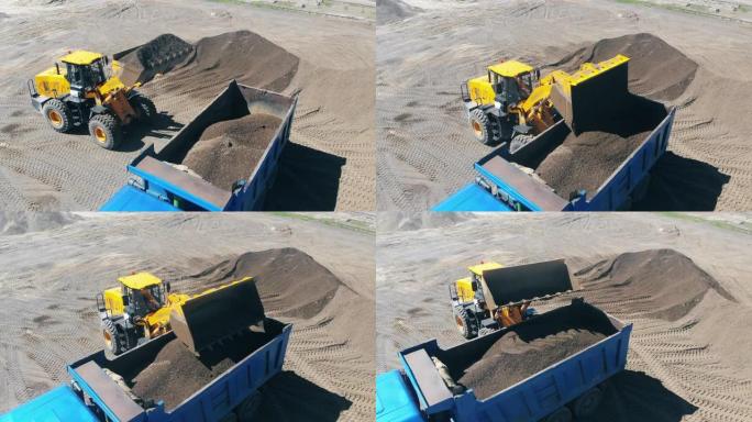 带有铲斗的拖拉机在机器上装载沙子和碎石。