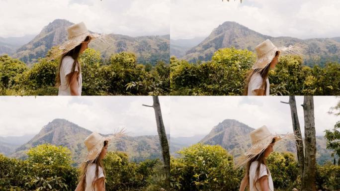侧视跟踪拍摄快乐的小女孩戴着大草帽沿着美丽的阳光明媚的森林山路散步。