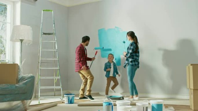 和小女儿在一起的家庭时光。年轻的父亲和母亲正在跳舞，并与油漆滚筒鬼混。墙漆颜色为浅蓝色。家里的房间准
