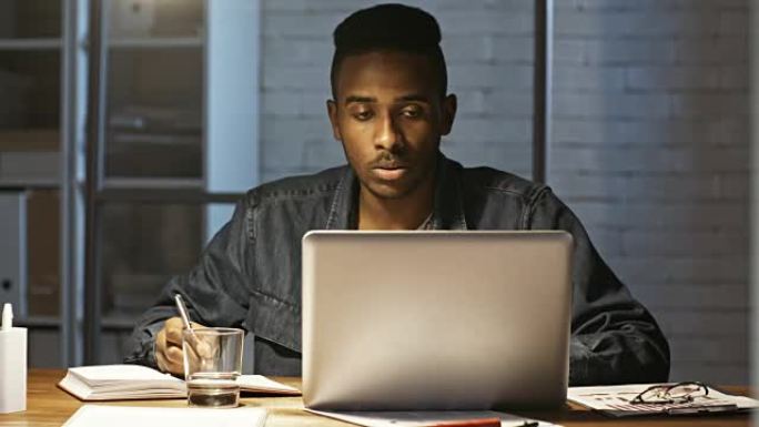 非洲文员晚上在笔记本电脑上工作