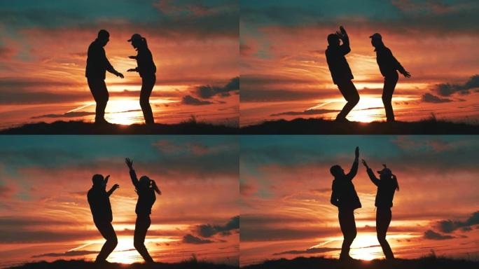 在日落背景上跳舞的男人和女人。慢动作
