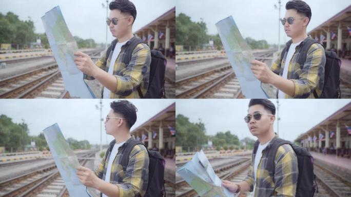 亚洲旅行者在度假旅行和火车站等候火车时，在地图上寻找方向，年轻的男性旅游背包客享受旅程。生活方式男人