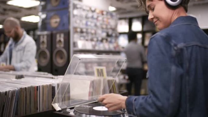 女人在唱片店的转盘上听黑胶唱片，然后摇曳音乐