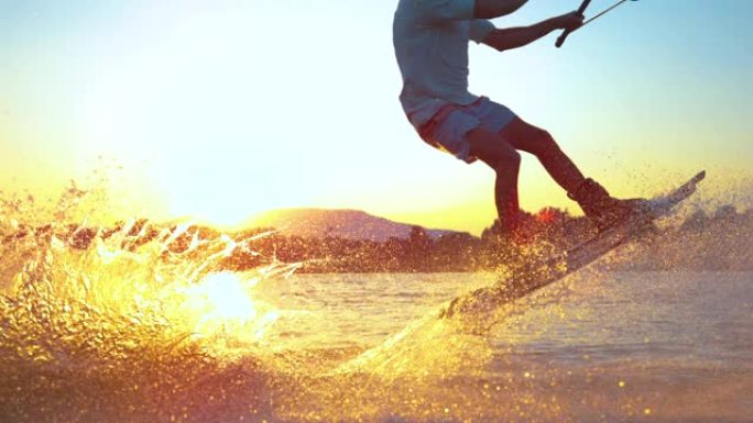 慢动作特写: 年轻的冲浪者在日落时滑水和跳跃180奥利