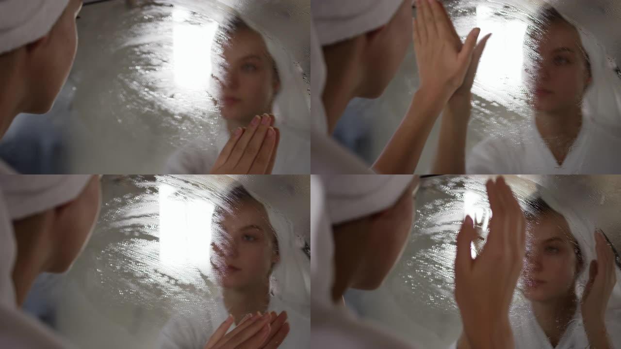 白人妇女在旅馆里从镜子上抹掉薄雾