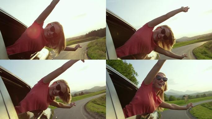 慢动作: 可爱的金发女人从车窗向外窥视，伸出双臂。