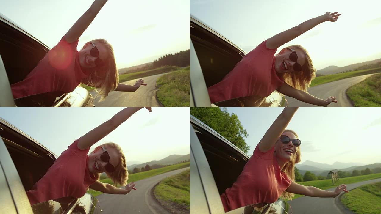 慢动作: 可爱的金发女人从车窗向外窥视，伸出双臂。