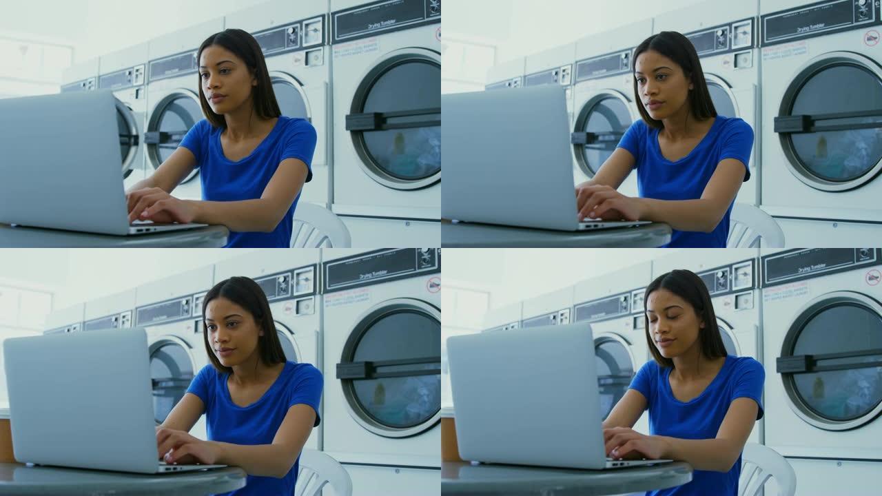 在4k自助洗衣店使用笔记本电脑的女人