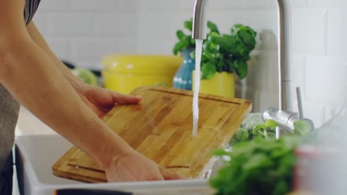 特写一个人在自来水下用清洗液清洗砧板的镜头。在现代厨房使用洗碗机。自然清洁的家庭和健康的生活理念。