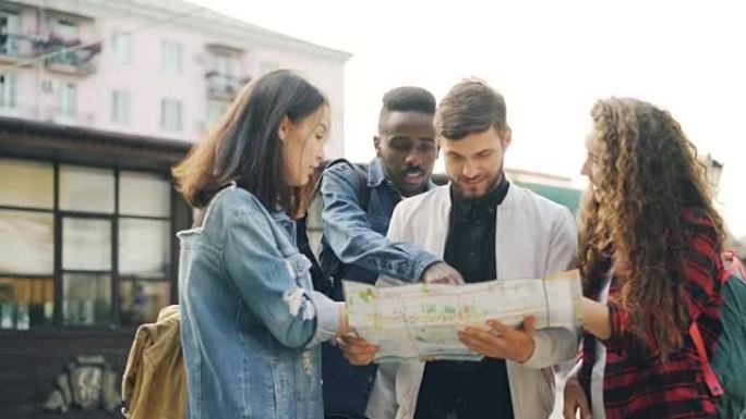 背着背包的年轻男女正看着地图站在外国城市的街道上，谈论旅程。航海、青年和旅游概念。