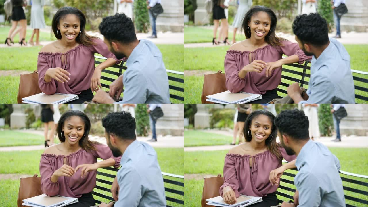 开朗的年轻大学夫妇在公园长椅上放松