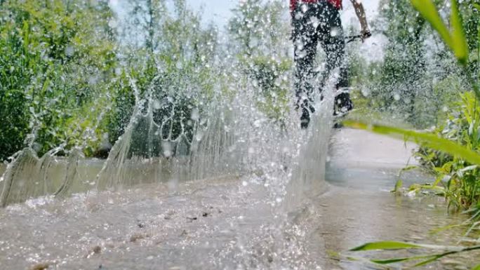 SLO MO (实时慢速) 骑自行车的人在水坑中执行自行车