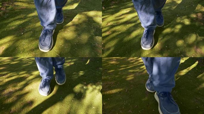男人穿着蓝色的裤子和蓝色的便鞋，在绿色的苔藓上穿过阳光和阴影。UHD