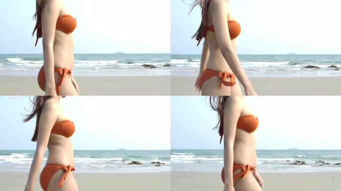 穿着比基尼的性感亚洲女人沿着海边散步。Steadicam慢动作镜头。夏季，旅行和美容概念。