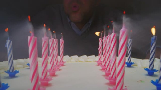 超级幻灯片在生日蛋糕的蜡烛和一个关掉蜡烛的人之间拍摄。