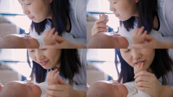 妈妈玩耍和亲吻婴儿的手