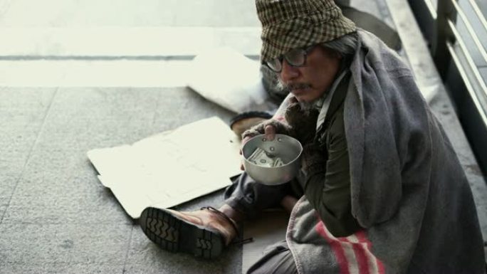 人们把钱捐给人行道上无家可归的乞讨碗。