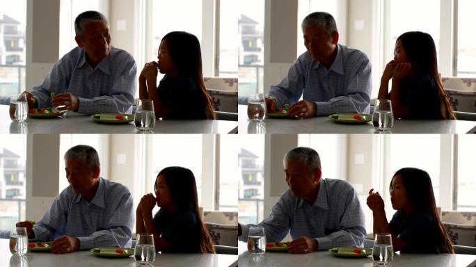 可爱的亚洲孙女和老爷爷吃食物的前视图餐桌4k