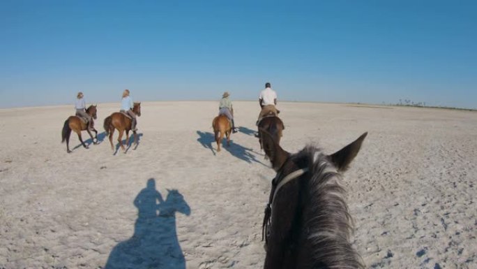 一群骑马者的慢动作视图在Makgadikgadi盐锅的广阔空间中慢跑