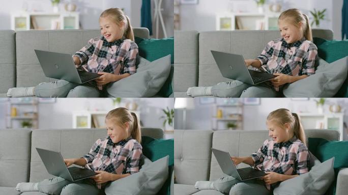 可爱的小女孩躺在沙发上，使用笔记本电脑，观看有趣的视频和卡通。