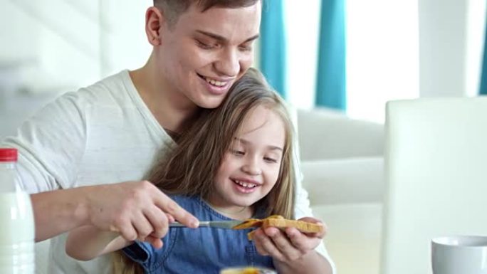 父亲为可爱的女孩在烤面包上放花生酱