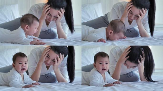 亚洲妈妈在卧室里带着可爱的小哭泣的婴儿感到疲倦。家庭关系，新生儿，人寿保险，生活方式，情感，关系和人