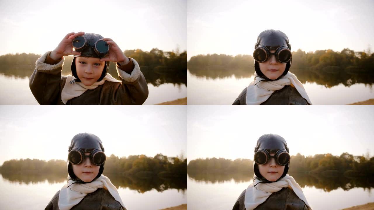 小男孩看着相机，戴着旧的飞行员眼镜，在湖边慢动作附近的惊人的阳光镜头耀斑中微笑