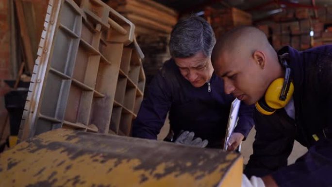 经理和员工在木材工厂检查机器，同时查看机器并讨论一些事情