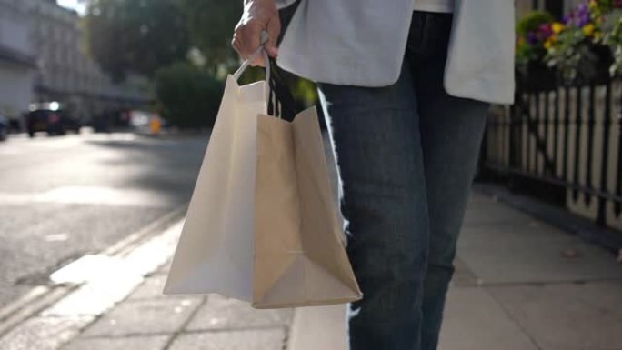 无法识别的高级妇女在购物狂潮中拿着袋子走在街上