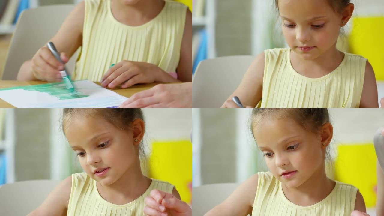 漂亮的小女孩用毡尖笔在纸上画画