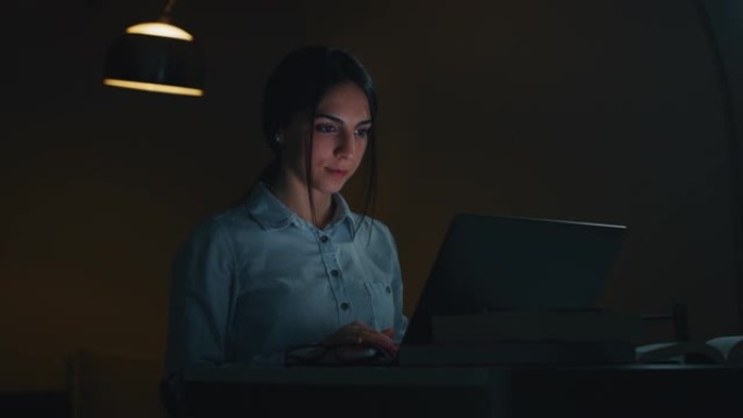 一个年轻漂亮的女商人的慢动作晚上在办公室里用电脑工作