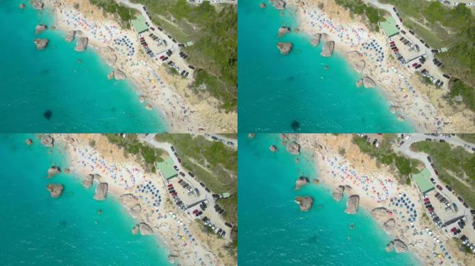 自上而下: 在拥挤的白色沙滩上飞翔，上面布满了五颜六色的雨伞。