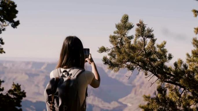 回顾快乐的旅游女人徒步旅行，拍摄令人惊叹的大峡谷国家公园山景的智能手机照片。