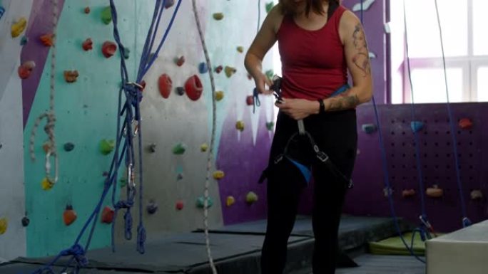 年轻的女登山者在室内健身房系上安全带