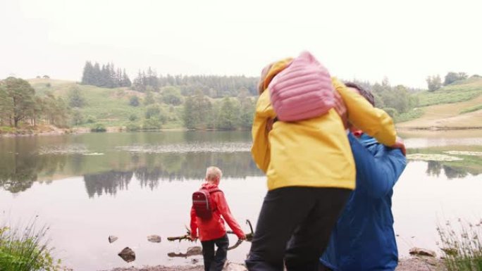 年轻的家庭走到湖边，在岸边玩耍，英国湖区