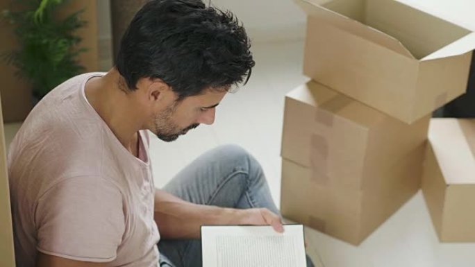 男子搬进新房子午后休闲时光翻书看书男子喝