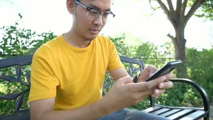 戴眼镜的SLO MO亚洲男子从智能手机上阅读好消息