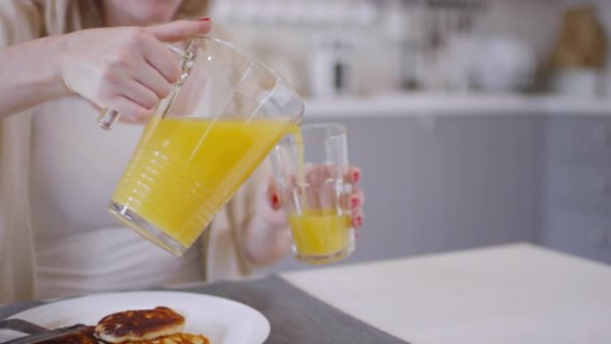 女人将橙汁倒入玻璃杯中