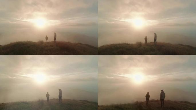 男人和女人站在日出的山顶上
