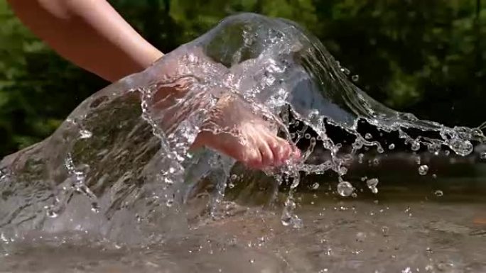 慢动作: 不知名的赤脚女孩踢，喷清爽的河水。