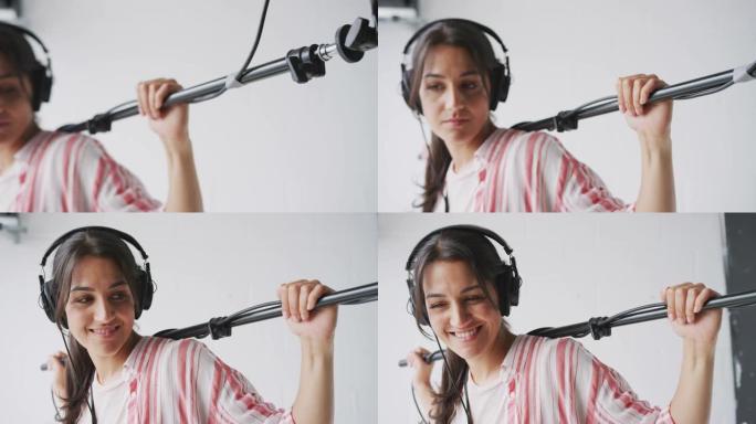 在白色工作室的视频电影制作中，女性录音师手持麦克风