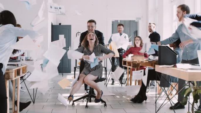 红色史诗-W 8К 快乐微笑的金发女商人玩得开心办公室同事扔纸在椅子上慢动作。