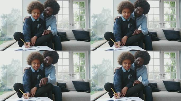 中年黑人父亲坐在他的儿子后面，在家里的客厅里帮助他十几岁的儿子做作业，前视图，特写镜头