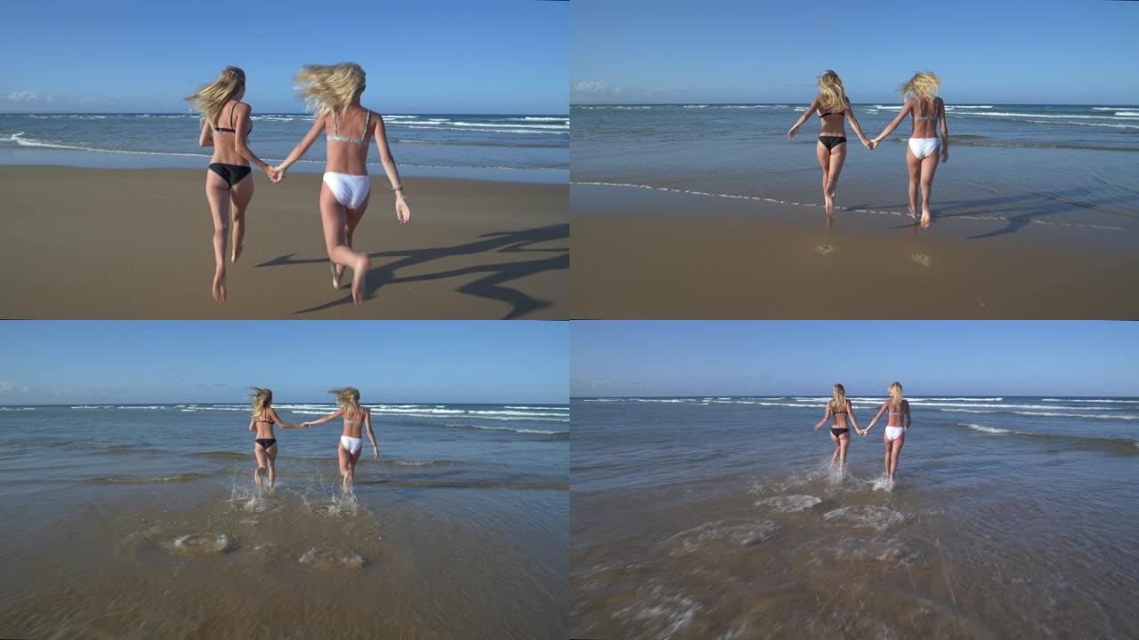 南非两个漂亮的年轻金发女人跑进海里的4k特写后视图