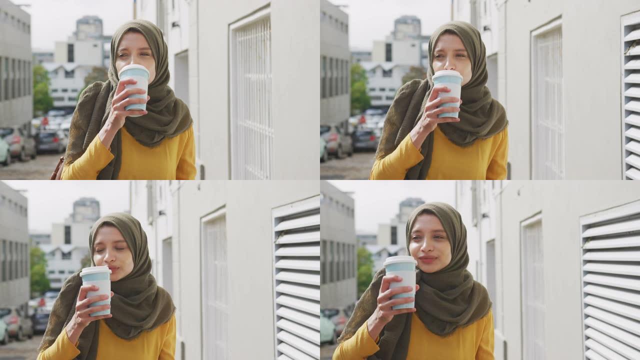 戴着头巾的女人在街上散步，喝着外卖咖啡
