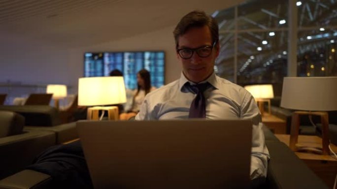 英俊的成年商人在笔记本电脑上工作，非常专注于机场的商务休息室