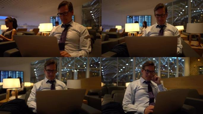 英俊的成年商人在笔记本电脑上工作，非常专注于机场的商务休息室