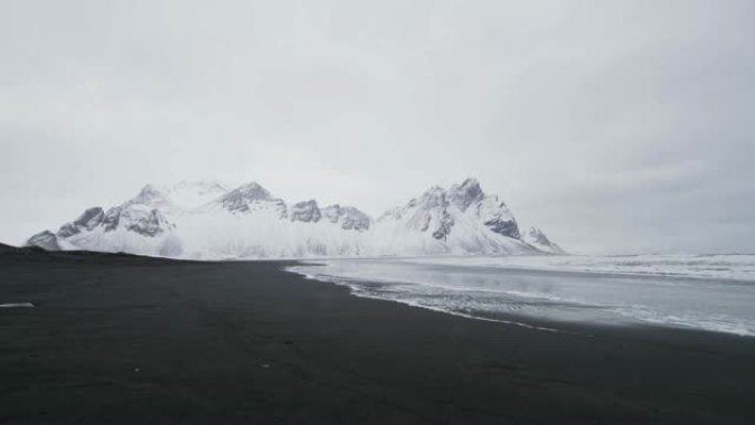 冰岛斯托克内斯海滩黑沙海滩外白雪覆盖的山脉